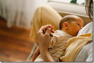 Newborn baby boy sucking milk from mothers breast. Portrait of mom and breastfeeding baby.