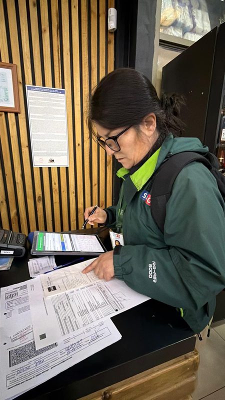 Fiscalizadores del Servicio Agrícola y Ganadero revisando etiquetas de botellas de alcohol en un establecimiento comercial