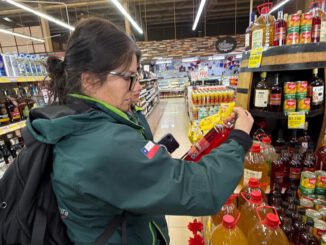 Fiscalizadores del Servicio Agrícola y Ganadero revisando etiquetas de botellas de alcohol en un establecimiento comercial