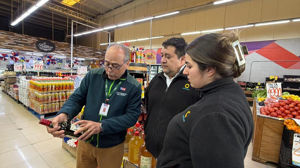 Fiscalizadores del Servicio Agrícola y Ganadero revisando etiquetas de botellas de alcohol en un establecimiento comercial