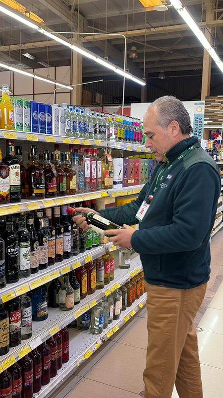 Fiscalizadores del Servicio Agrícola y Ganadero revisando etiquetas de botellas de alcohol en un establecimiento comercial