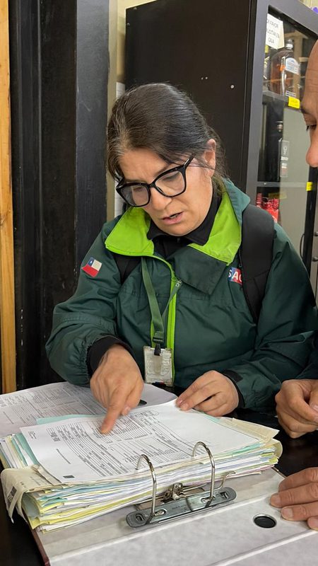 Fiscalizadores del Servicio Agrícola y Ganadero revisando etiquetas de botellas de alcohol en un establecimiento comercial