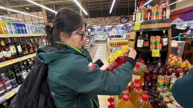 Fiscalizadores del Servicio Agrícola y Ganadero revisando etiquetas de botellas de alcohol en un establecimiento comercial